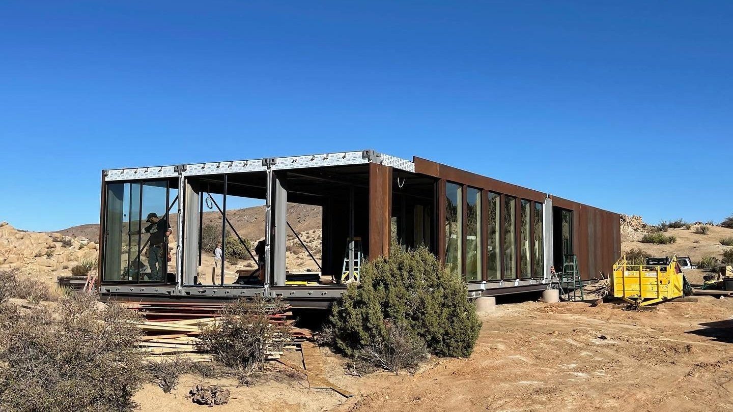 Ranch home under construction with steel framing and glass walls