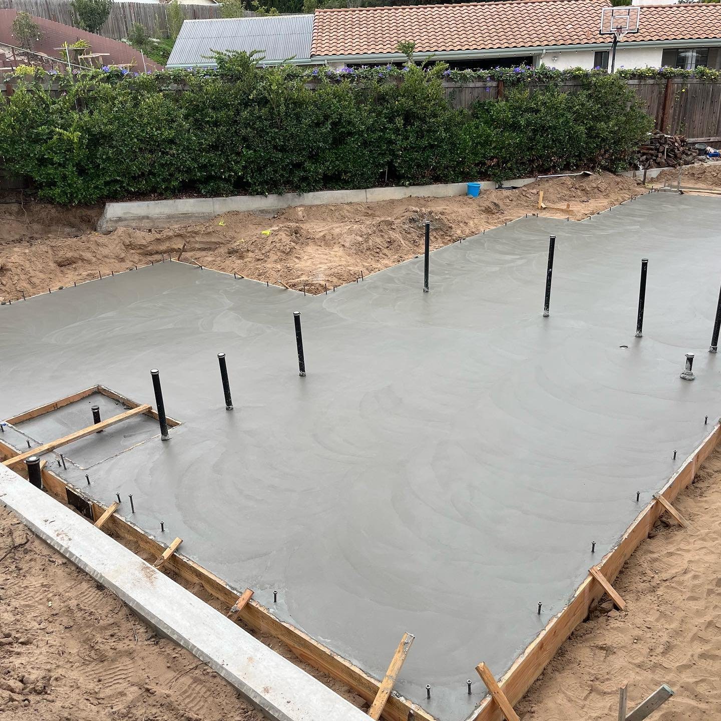 Freshly poured residential concrete slab with forms and anchor bolts