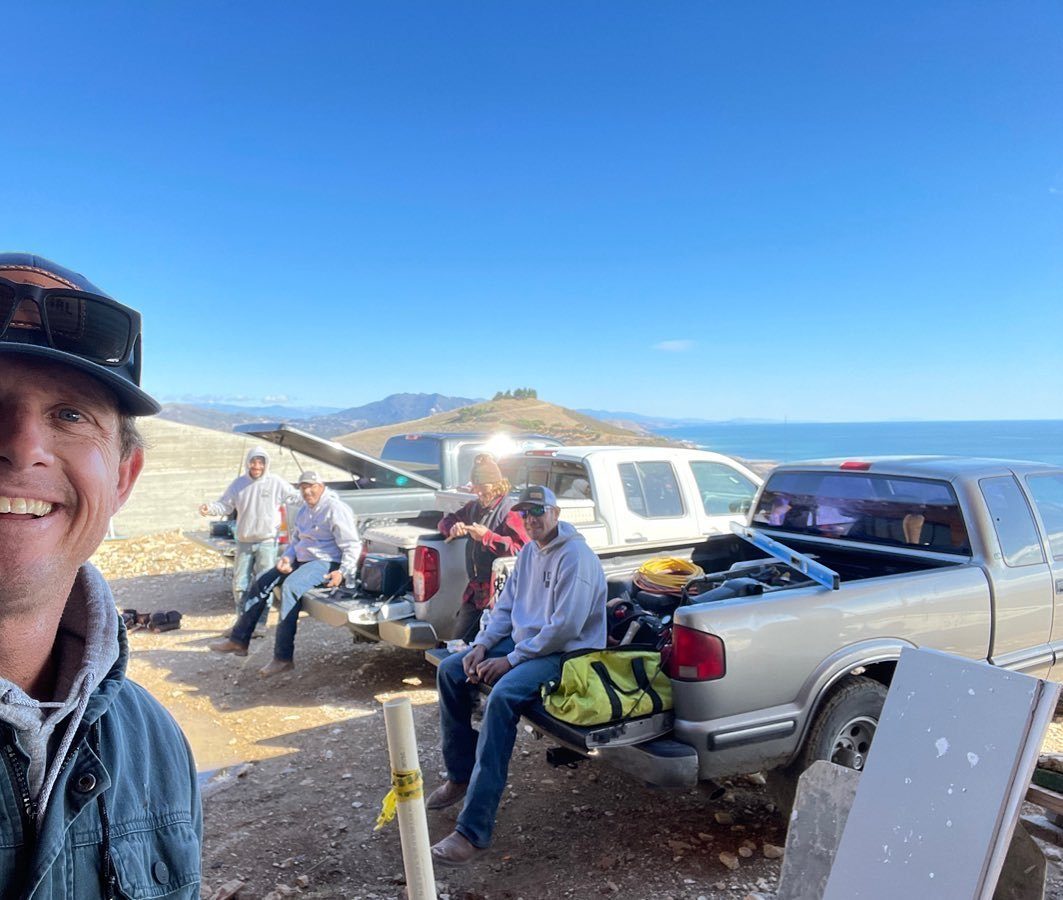 JD Green Construction crew taking a break beside work trucks on a coastal job site